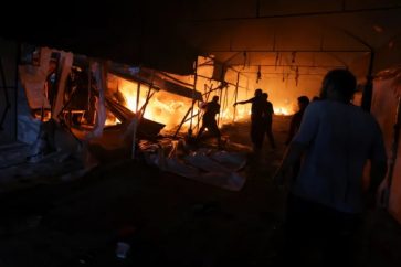 People attempt to extinguish a fire at the scene of an Israeli attack on tents sheltering displaced people in the courtyard of Al-Aqsa Martyrs Hospital (October 14, 2024).