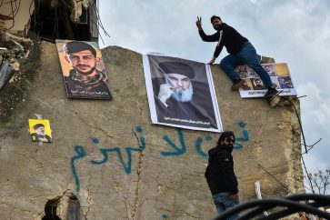 People hang a portrait of slain Hezbollah leader Hassan Nasrallah (C) and portraits of other Hezbollah fighters killed during the conflict with Israel on the rubble of their house in the southern Lebanese village of Kfar Kila near the border with Israel on February 19, 2025. Israeli forces withdrew from a series of border villages including southeast Lebanon's Odaisseh, Kfar Kila, Mais al-Jabal, Markaba and Hula under an extended ceasefire deadline that expired on February 18, but remained in five points near the border. (Photo by Fadel ITANI / AFP)